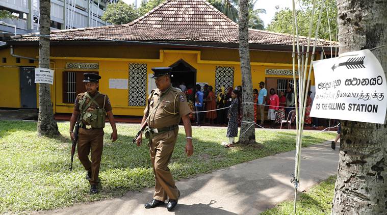 Sri Lankans queue to cast their votes as police officers patrol at a polling station during the presidential election in Colombo, Sri Lanka, Saturday, Nov. 16, 2019. Polls opened in Sri Lanka’s presidential election Saturday after weeks of campaigning that largely focused on national security and religious extremism in the backdrop of the deadly Islamic State-inspired suicide bomb attacks on Easter Sunday. (AP Photo/Eranga Jayawardena)