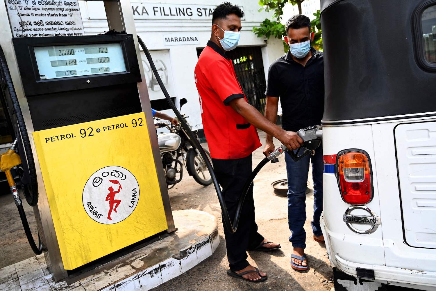 A worker fills the tank of an auto rickshaw at a petrol station in Colombo on February 18, 2022. (Photo by Ishara S. KODIKARA / AFP)