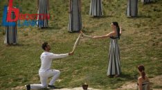 First torch bearer, rowing Olympic gold medalist on 2020, Stephanos Ntouskos (L) receives the flame from Greek actress Mary Mina, playing the role of the High Priestess, as he starts his run with the Olympic torch following the flame lighting ceremony for the Paris 2024 Olympics Games at the Ancient Olympia archeological site, birthplace of the ancient Olympics in southern Greece, on April 16, 2024.  (Photo by Angelos Tzortzinis / AFP)